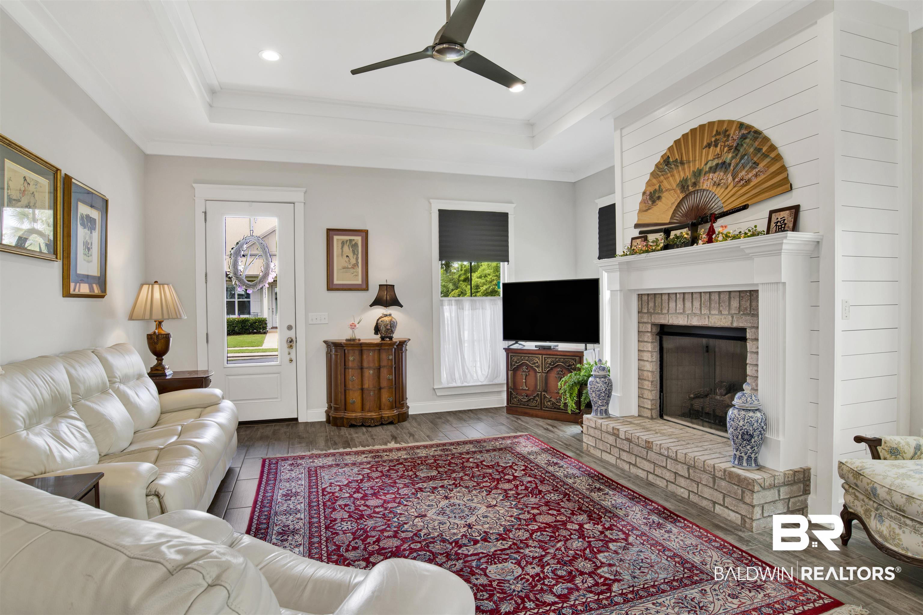 23893 Cypress Crossing Orange Beach, AL 36561 - Photo 3 of 22 Living room with a raised ceiling, healthy amount of natural light, a ceiling fan, wood finished floors, and crown molding
