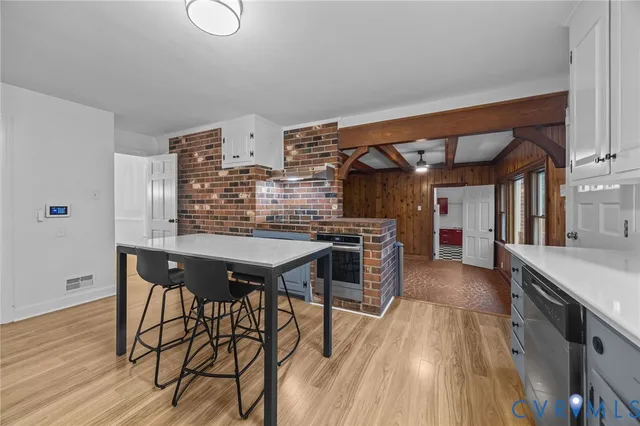 a open kitchen with stainless steel appliances kitchen island granite countertop a table chairs in it and wooden floors