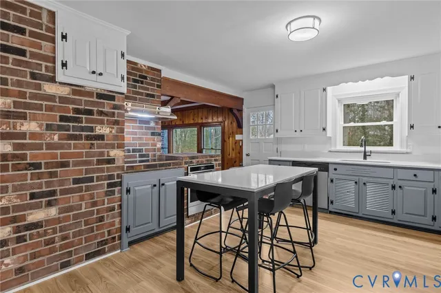 a kitchen with stainless steel appliances kitchen island granite countertop a table chairs sink and cabinets