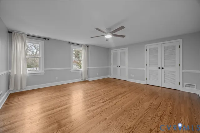 a view of empty room with wooden floor and fan