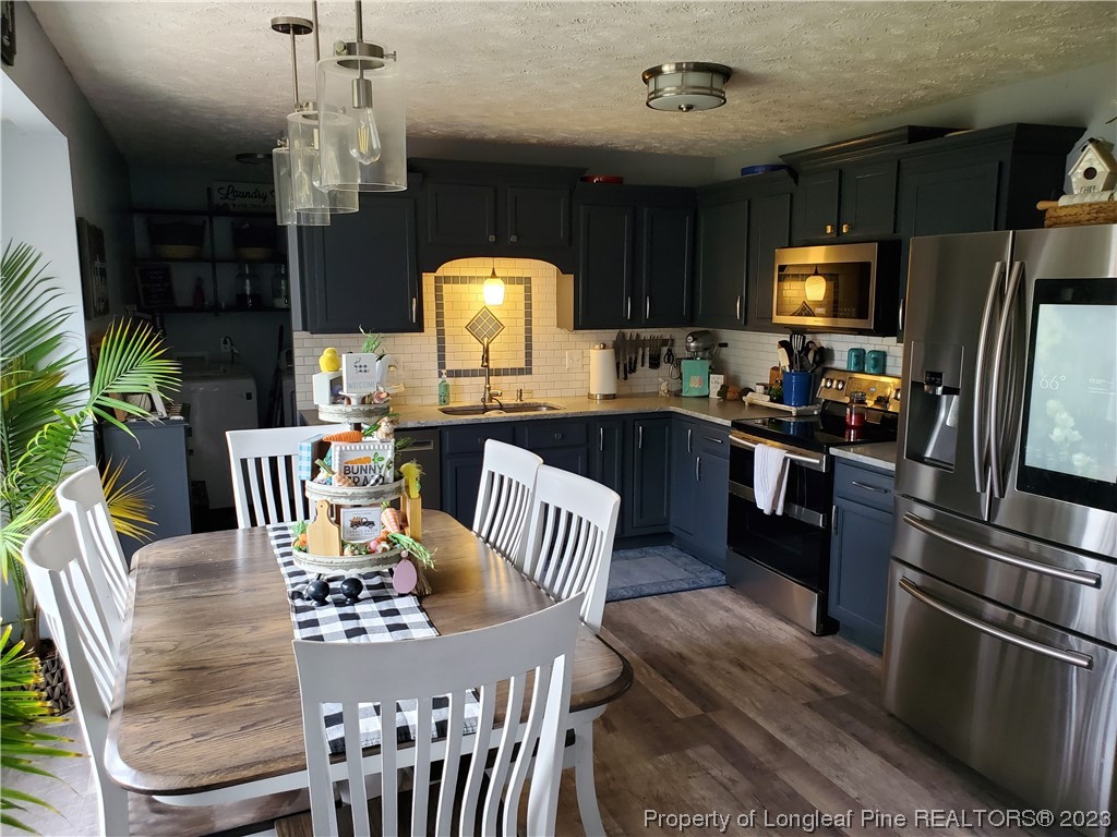 563 Sawyer Road Cameron, NC 28326 - Photo 24 of 43 a kitchen with stainless steel appliances granite countertop a sink dishwasher a dining table and chairs with wooden floor
