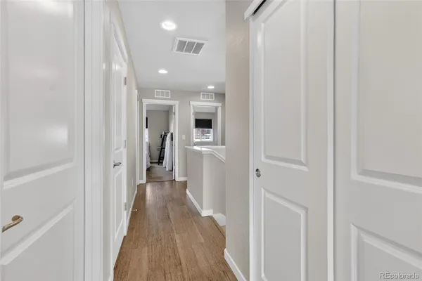 a view of a hallway with wooden floor and a bathroom