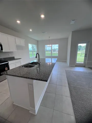 a large kitchen with granite countertop a sink and a stove top oven