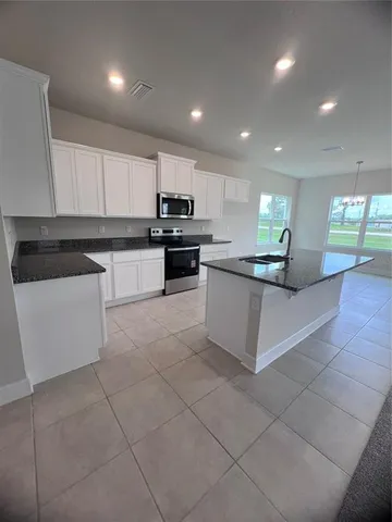 a kitchen with stainless steel appliances kitchen island granite countertop a sink and white cabinets