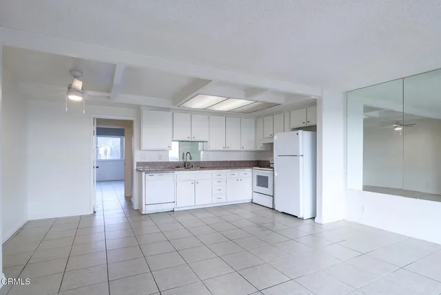 a large kitchen with a refrigerator and white cabinets