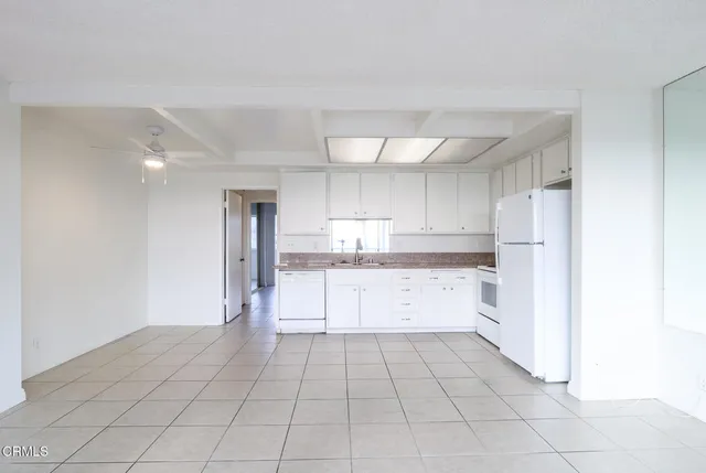 a large white kitchen with cabinets and a refrigerator