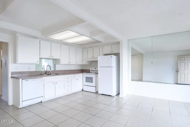 a kitchen with a sink a refrigerator and white cabinets