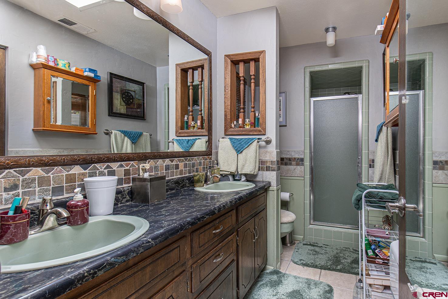 904 Florida Road Durango, CO 81301 - Photo 11 of 20 a bathroom with a granite countertop sink a mirror and shower
