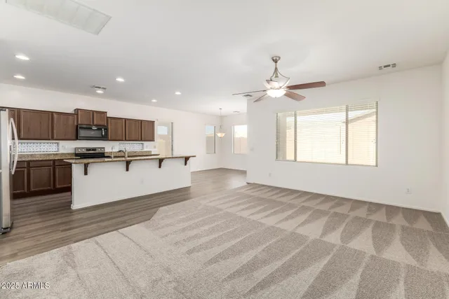 a large white kitchen with kitchen island a stove a sink dishwasher and a refrigerator with wooden floor