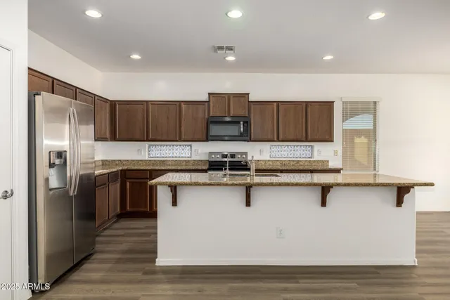 a kitchen with granite countertop kitchen island stainless steel appliances a sink stove and cabinets