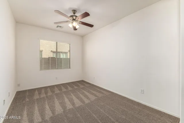 an empty room with closet and a ceiling fan