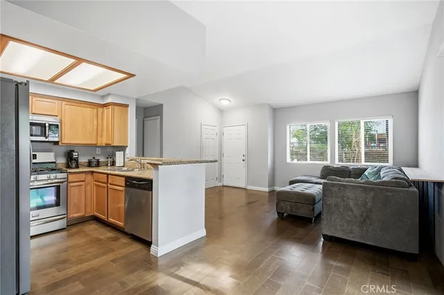 a living room with stainless steel appliances granite countertop furniture and a large window