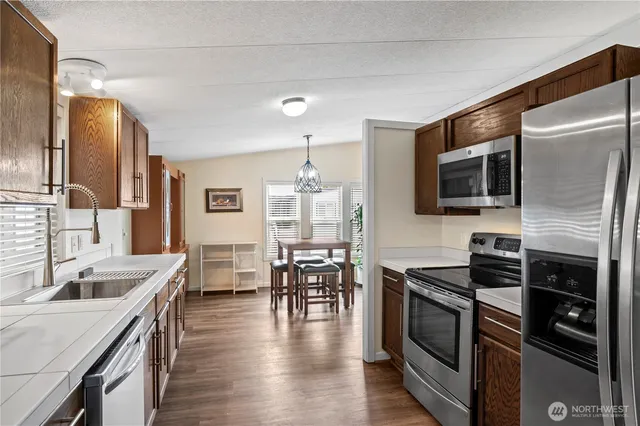 a kitchen with stainless steel appliances granite countertop a stove top oven a sink dishwasher a dining table and chairs with wooden floor