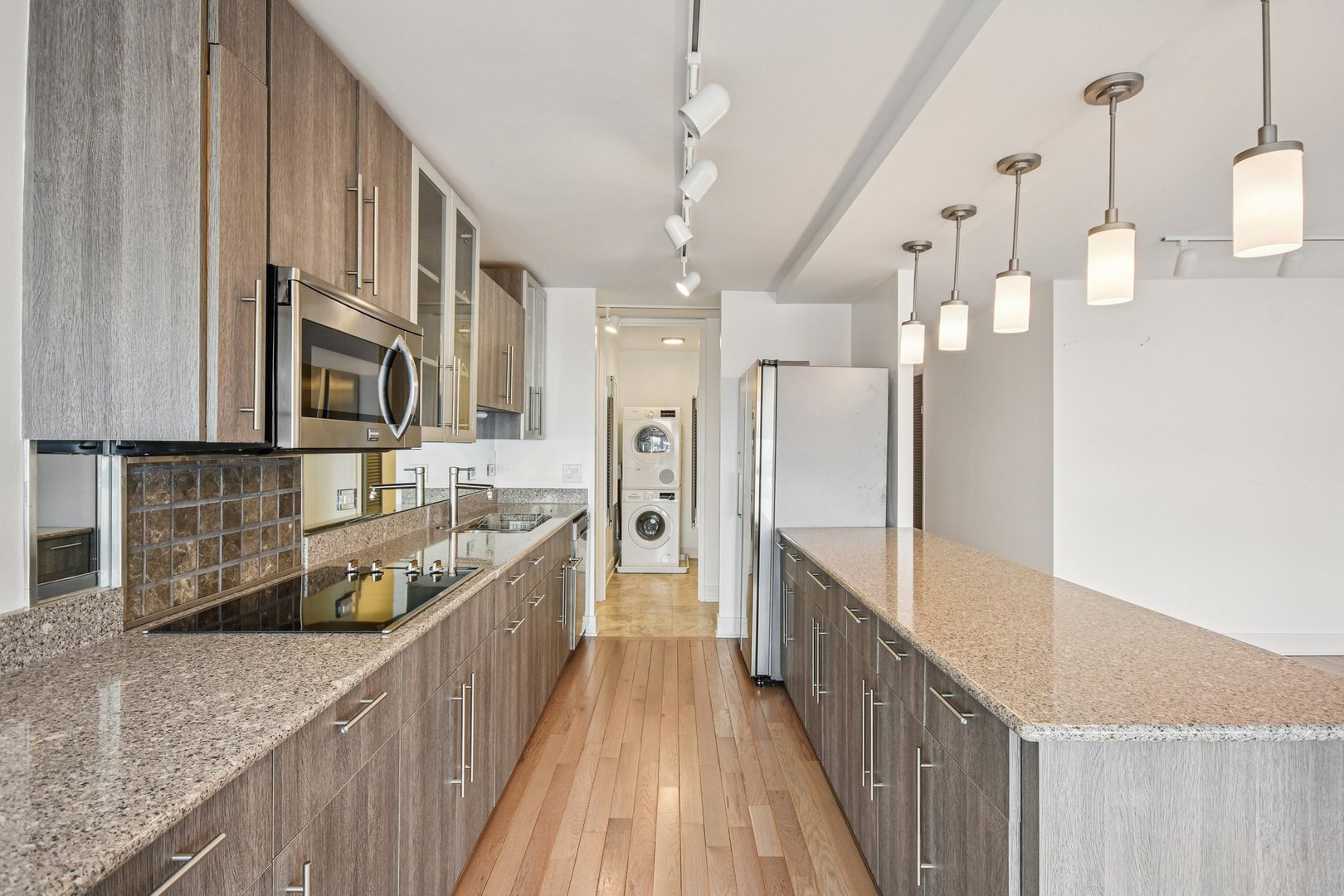 360 East Randolph Street, Unit 1102 Chicago, IL 60601 - Photo 7 of 27 a large kitchen with granite countertop a large counter top a sink a refrigerator and wooden floors