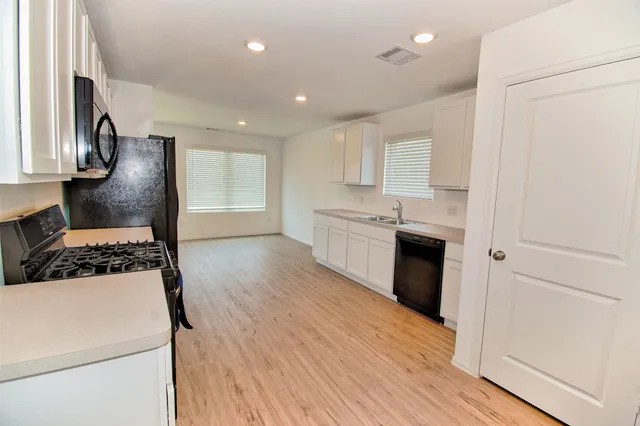 a kitchen with a sink a stove top oven and wooden floor