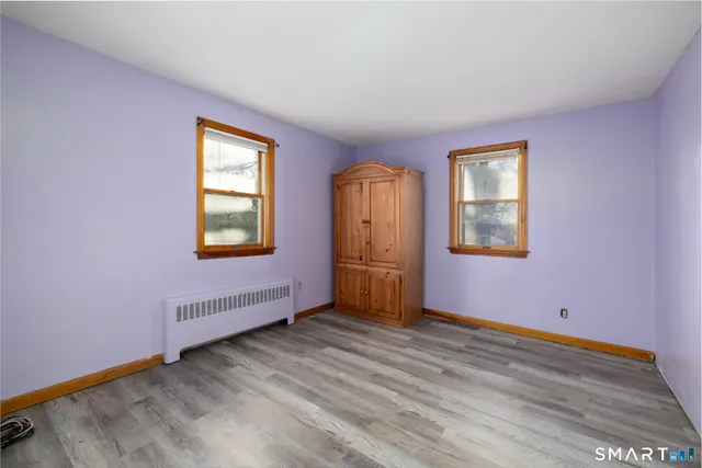 a view of an empty room with window and wooden floor