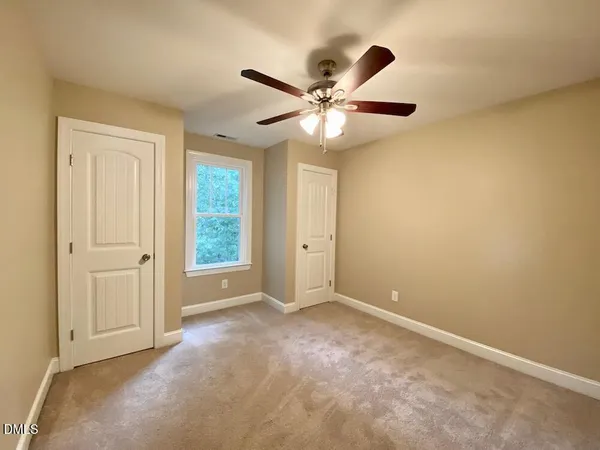 an empty room with windows and fan