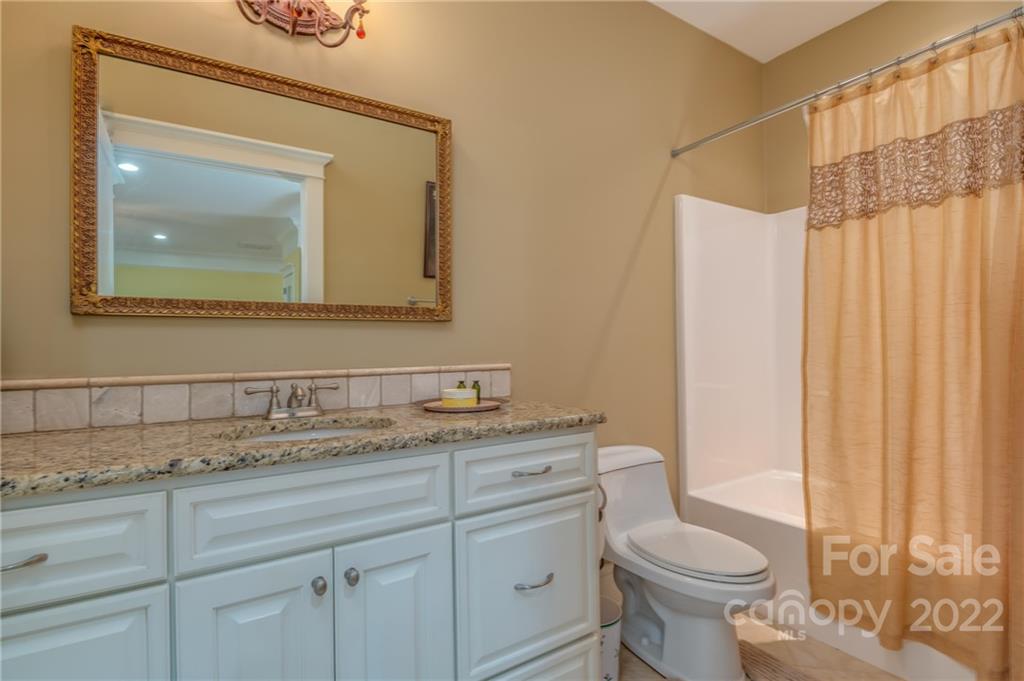 2221 Pea Ridge Road Mill Spring, NC 28756 - Photo 34 of 48 a bathroom with a granite countertop sink a toilet and a mirror