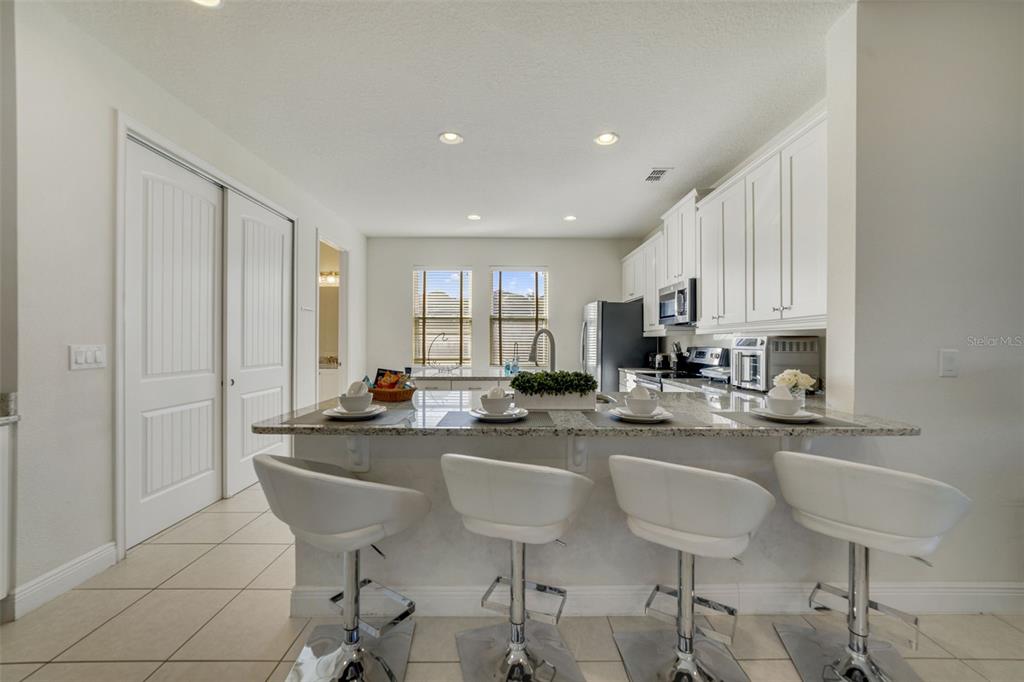 180 Minton Loop Kissimmee, FL 34747 - Photo 13 of 49 a kitchen with stainless steel appliances granite countertop a sink a stove a dining table and chairs