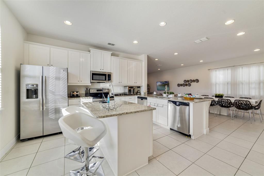 180 Minton Loop Kissimmee, FL 34747 - Photo 14 of 49 a kitchen with stainless steel appliances granite countertop a refrigerator a sink a stove a dining table and chairs