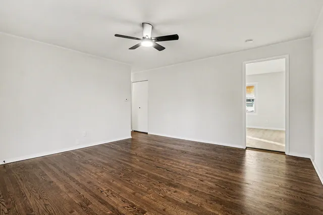 an empty room with wooden floor fan and windows