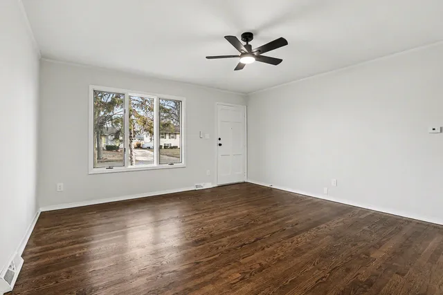 a view of empty room with wooden floor and fan