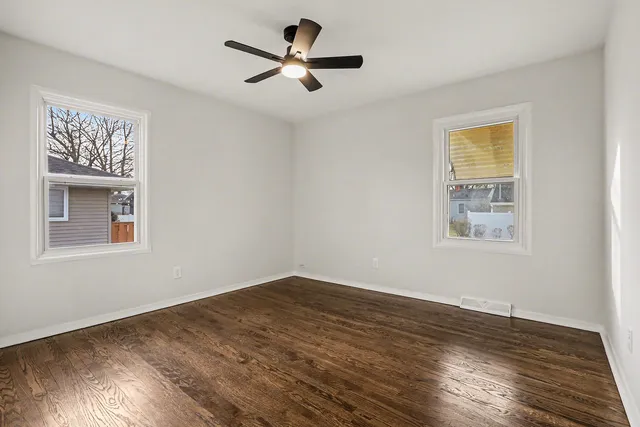 a view of empty room with wooden floor and fan