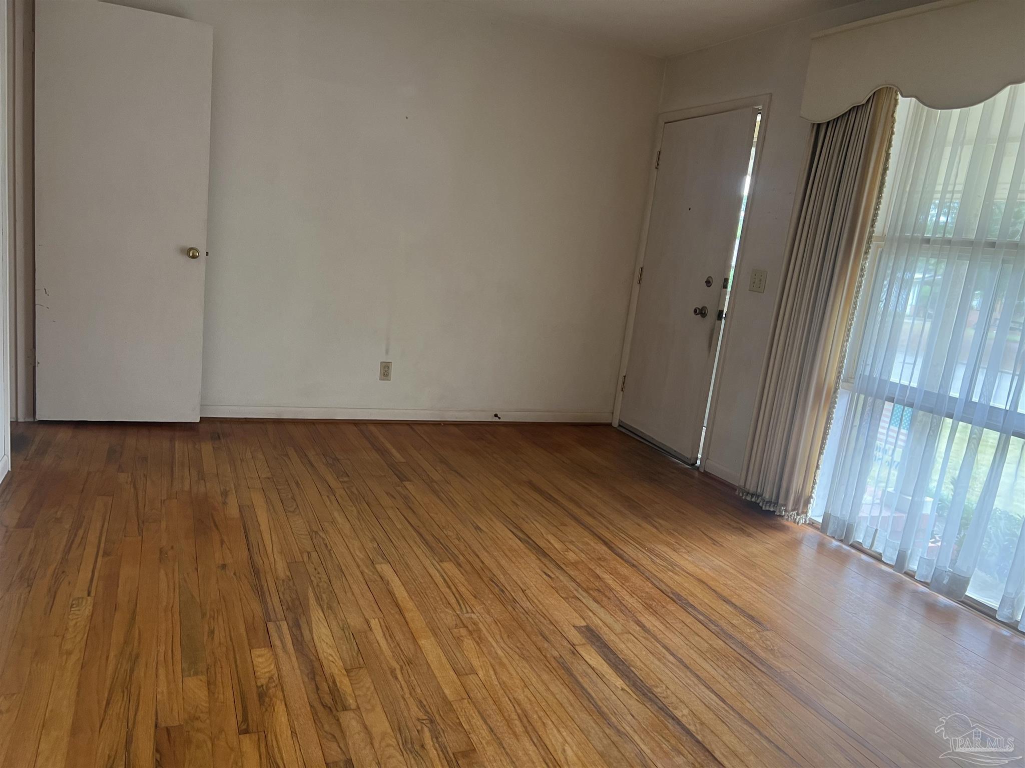 6020 Hilltop Road Pensacola, FL 32504 - Photo 3 of 27 a view of an empty room with wooden floor and a window