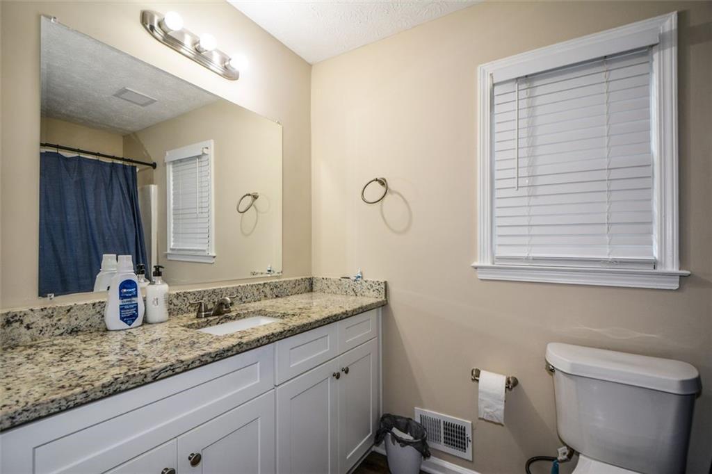 2895 Fairview Road Covington, GA 30016 - Photo 17 of 31 a bathroom with a granite countertop sink a toilet and a mirror