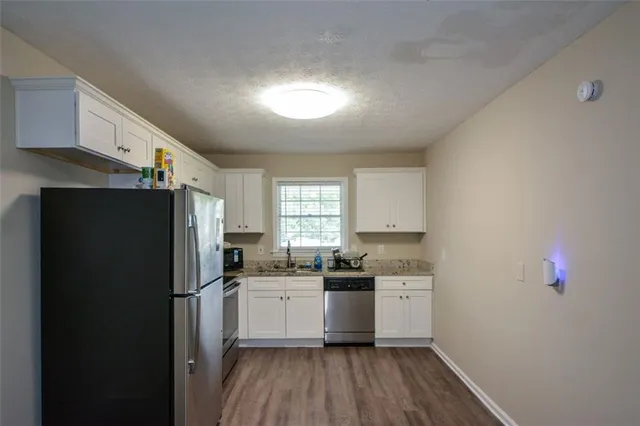 a kitchen with stainless steel appliances a refrigerator sink and wooden floor