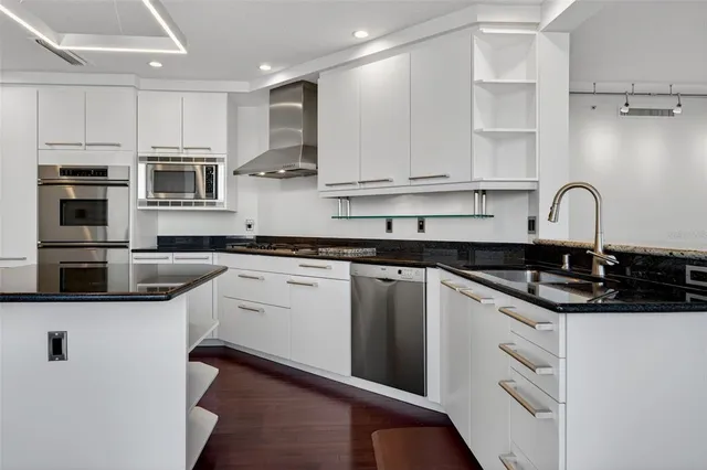 a kitchen with granite countertop white cabinets and wooden floor