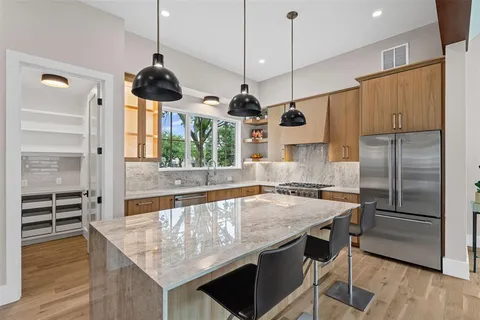 a kitchen with stainless steel appliances granite countertop a kitchen island a stove and a wooden floors