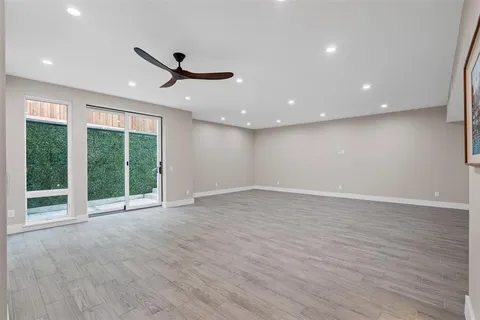 a view of an empty room with wooden floor and windows