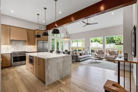 a kitchen with stainless steel appliances granite countertop a stove and a large window with wooden floors