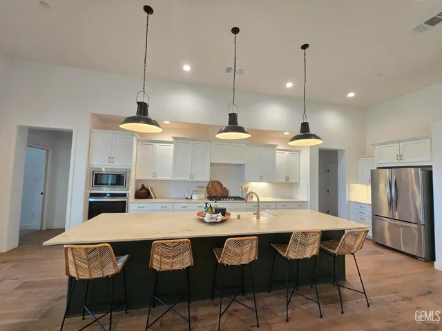 a kitchen with granite countertop a table a stove a refrigerator a dining table chairs and cabinets