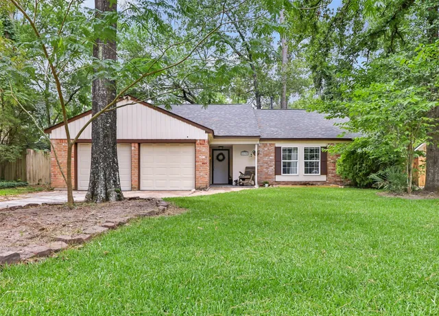 a view of a yard in front of a house with plants and large tree