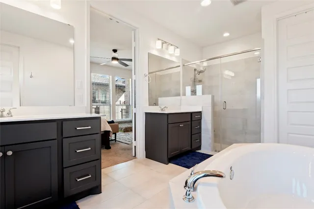 a bathroom with a tub sink double vanity and a mirror