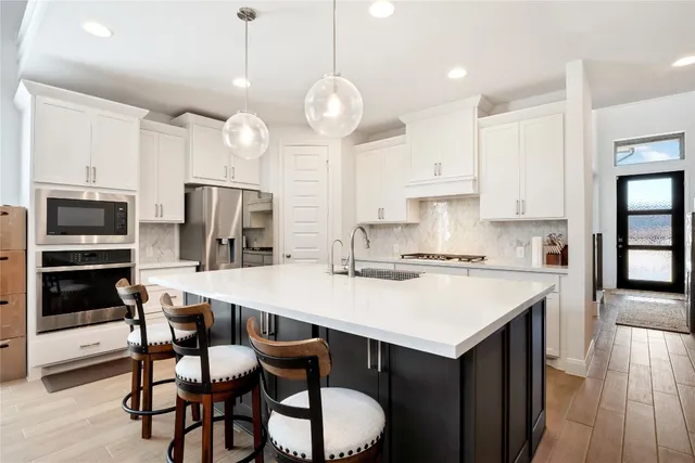 a kitchen with a dining table chairs stainless steel appliances and cabinets
