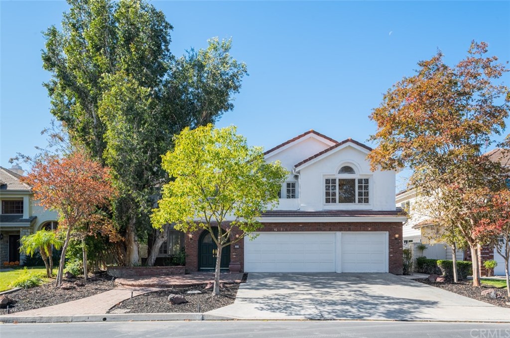 a front view of a house with a yard and tree s