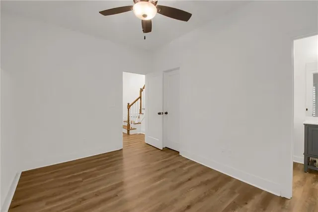 an empty room with wooden floor chandelier fan and entryway