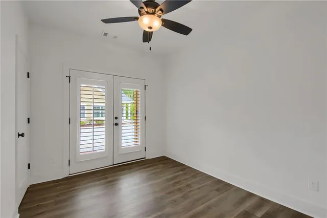 an empty room with wooden floor fan and windows