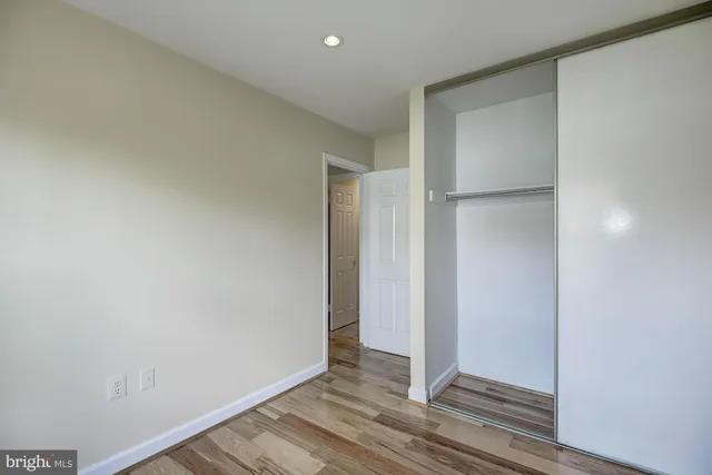 an empty room with wooden floor & closet area