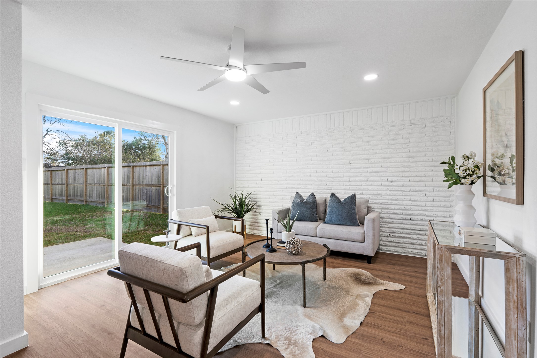 5023 Redstart Street Houston, TX 77035 - Photo 19 of 34 Transition through sliding glass doors to a bright, versatile living space featuring a stunning white-painted brick accent wall and views of the private backyard.