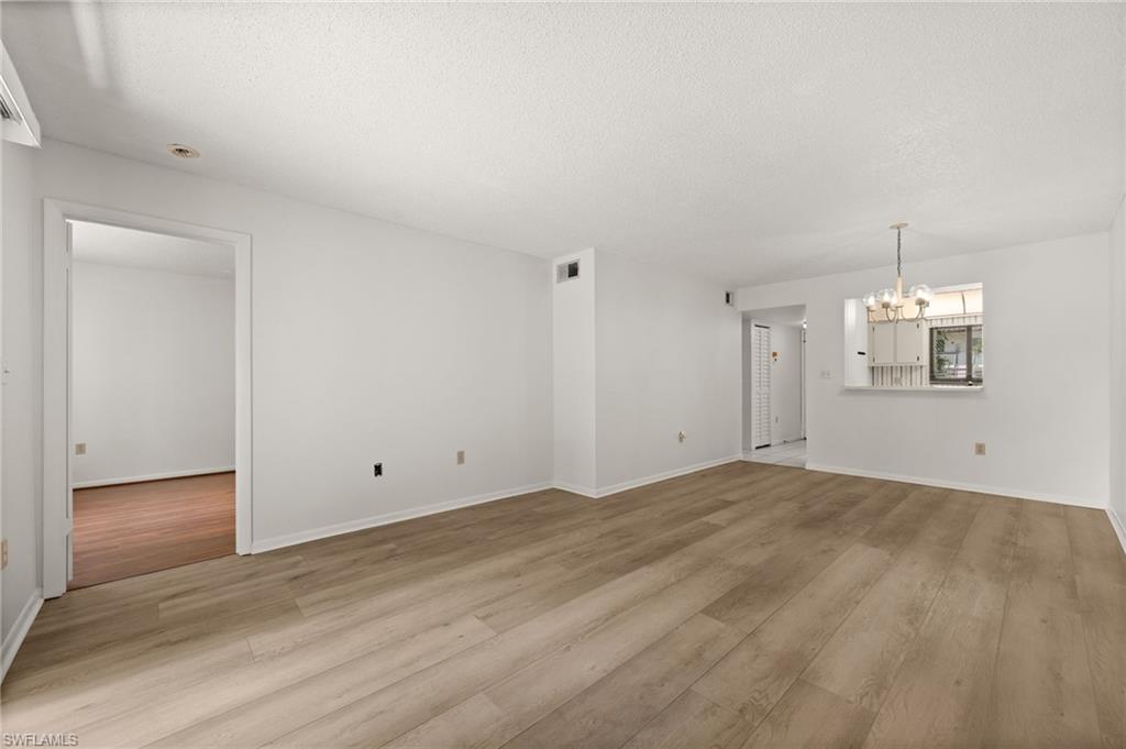 4251 27th Court Southwest, Unit 104 Naples, FL 34116 - Photo 7 of 22 an empty room with wooden floor and windows