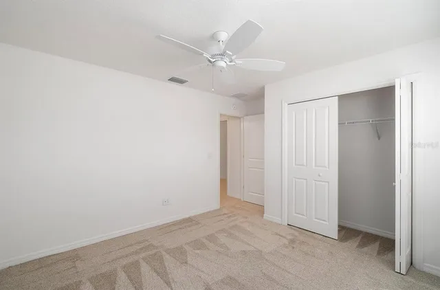 an empty room with a ceiling fan and closet area