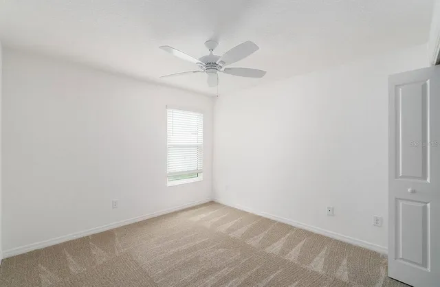 an empty room with windows and fan