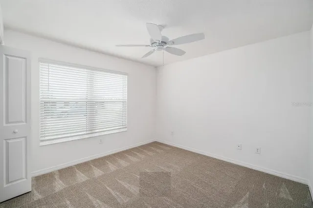 an empty room with a window and a fan