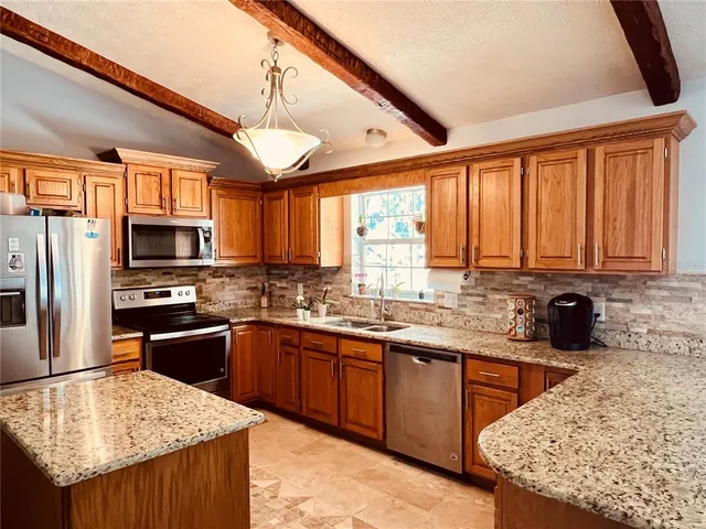 a kitchen with stainless steel appliances granite countertop wooden cabinets a stove top oven a sink and dishwasher