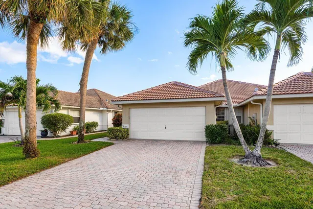 a front view of a house with a garden and palm trees
