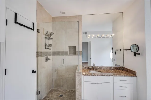 a bathroom with a granite countertop sink a mirror and shower